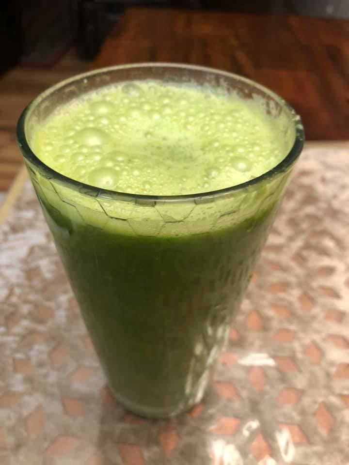 A glass with green smoothie filled to the brim